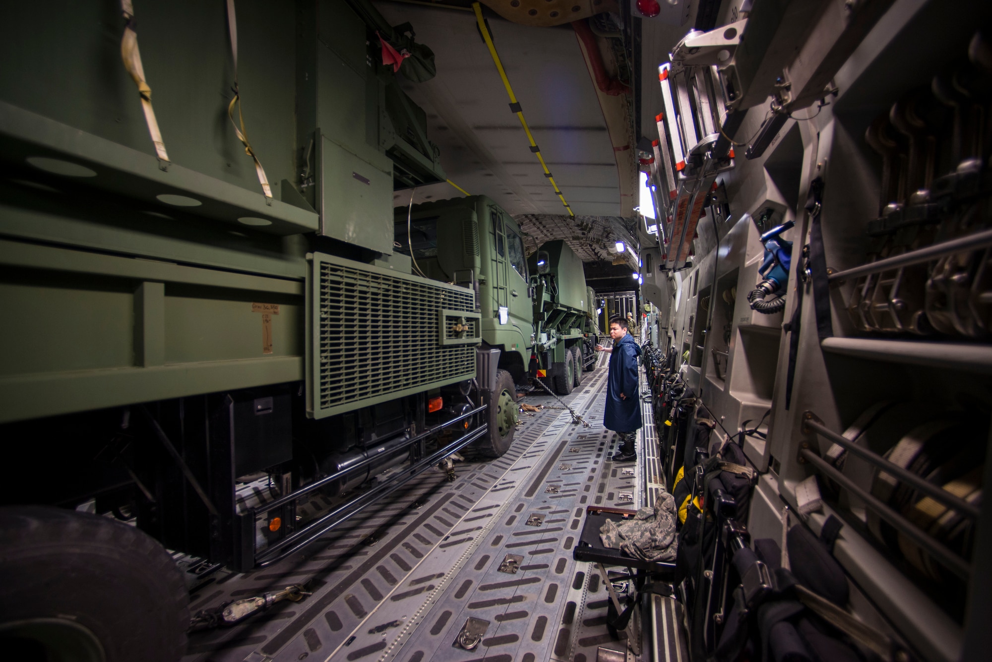 A Japan Air Self- Defense member observes as members of the 730th Air Mobility Squadron secure two engagement command station vehicles prior to take-off at Yokota Air Base, Japan, Nov. 06, 2014. The vehicles were loaded for the first time ever onto the C-17 Globemaster III during Keen Sword 2015. (U.S. Air Force photo by Tech. Sgt. Melissa K. Mekpongsatorn/Released) 