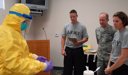 Maj Gen. Donald Dunbar, the adjutant general of Wisconsin, looks on as a member of the Wisconsin National Guard’s Joint Health Assistance Team decontaminates her protective suit during training for an Ebola Virus Disease response Oct. 31 at Volk Field, Wisconsin. 