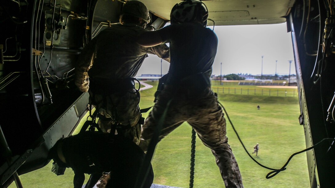 Cpl. Caleb Owens, from Melbourne, Iowa, prepares to fast-rope out of an MV-22B Osprey tiltrotor aircraft with his military working dog, Dixie, Oct. 27 at Camp Hansen. After familiarizing themselves with fast-roping techniques by executing them with no gear, the Marines worked their way up to wearing full gear and then with their military working dogs as well. Owens is a military policeman, and a working dog handler. He and Dixie are with 3rd Law Enforcement Battalion, III Marine Expeditionary Force Headquarters Group, III MEF. 