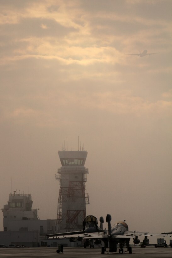 Aircraft mechanics inspect the cockpit of an EA-6B Prowler as a KC-130J Super Hercules belonging to Marine Aerial Refueler Transport Squadron 252 rises through a low cloud cover toward the southeast after lifting off the runway at Marine Corps Air Station Cherry Point, N.C., Nov. 17, 2014. 
Cherry Point is home to 2nd Marine Aircraft Wing and several of its squadrons. Cherry Point's runways operate 24/7, 365 days each year, and the air station hosts squadrons that specialize in air-to-ground attack support; electronic warfare; aerial transport and refueling; and sea and land search and rescue.