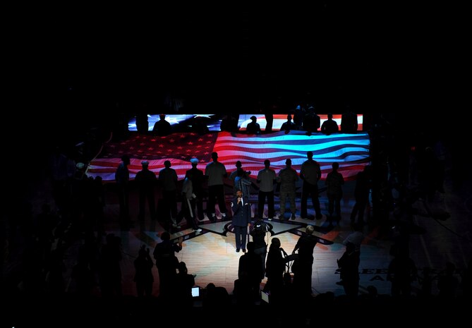 Master Sgt. Cedrick Coward, 940th Reserve Wing, sings the National Anthem as military and Sacramento Kings members hold the American Flag during Military Appreciation Night at the Sleep Train Arena in Sacramento, Calif., Nov. 15, 2014. The Kings defeated the San Antonio Spurs, 94-91. (U.S. Air Force photo by Staff Sgt. Robert M. Trujillo/Released)