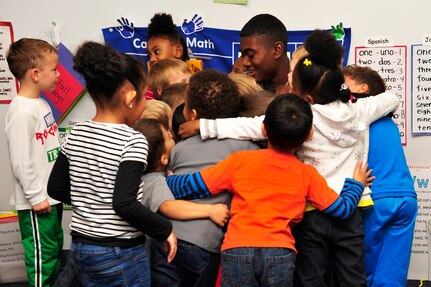 Airman 1st Class Bradley Simmons, 1st Maintenance Squadron ammunitions technician receives a hug from the children after reading to them at the Child Development Center at Langley Air Force Base, Va., Nov. 13, 2014. As the team leader for the Reading Enriches Children Program, Simmons recruits volunteers to read out loud to homeless and at-risk children at shelters. (U.S. Air Force photo by Airman 1st Class Breonna Veal/Released)