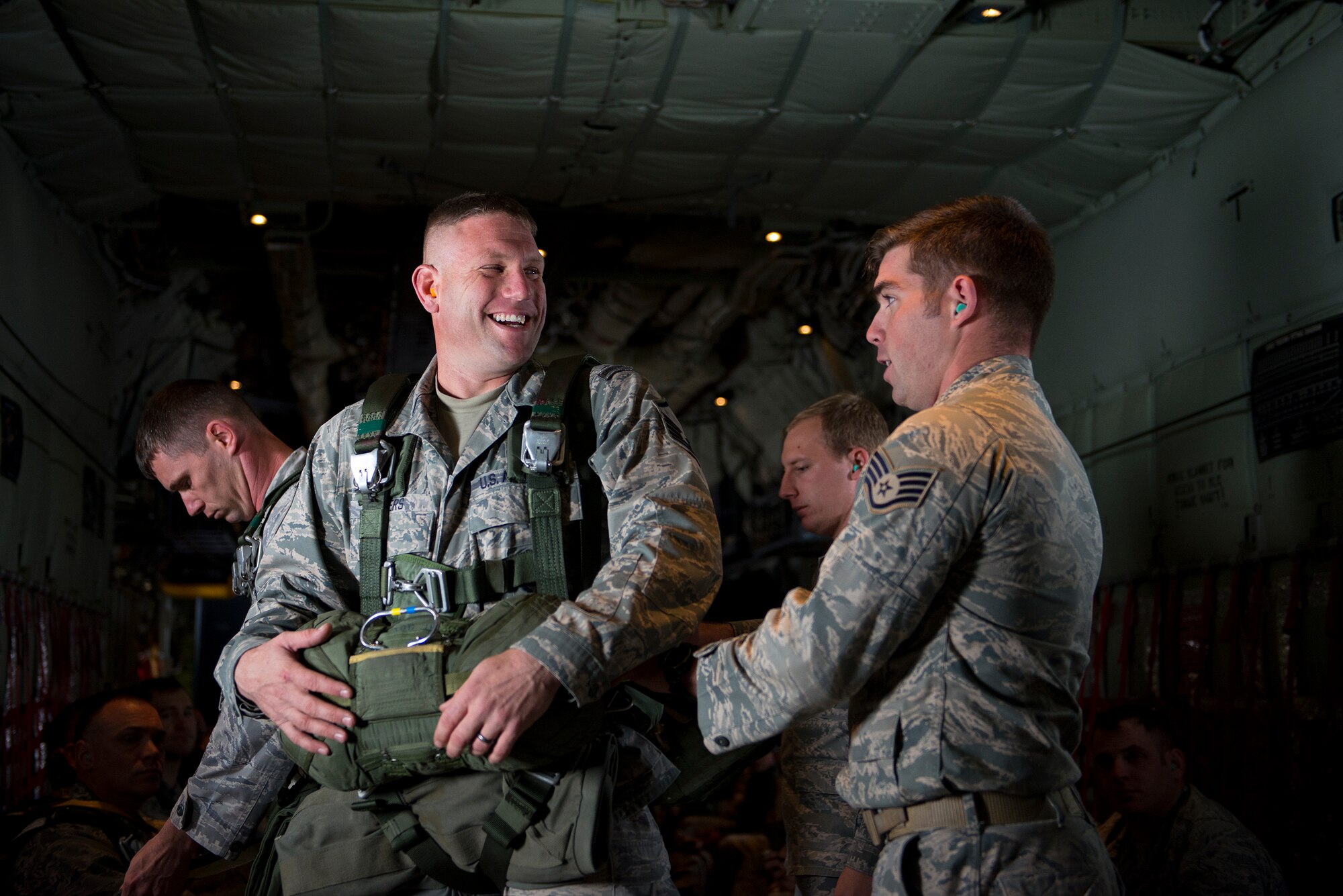 U.S. Air Force Master Sgt. Justin Geers, left, 823d Base Defense Squadron jumpmaster, laughs while Staff Sgt. Steven Trimble, 820th Combat Operations Squadron jumpmaster, performs a jumpmaster personnel inspection (JMPI) Nov. 13, 2014, over Moody Air Force Base, Ga. Prior to each jump, a jumpmaster conducts a JMPI to ensure each jumper’s parachute is properly prepared. (U.S. Air Force photo by Airman 1st Class Ryan Callaghan/Released)