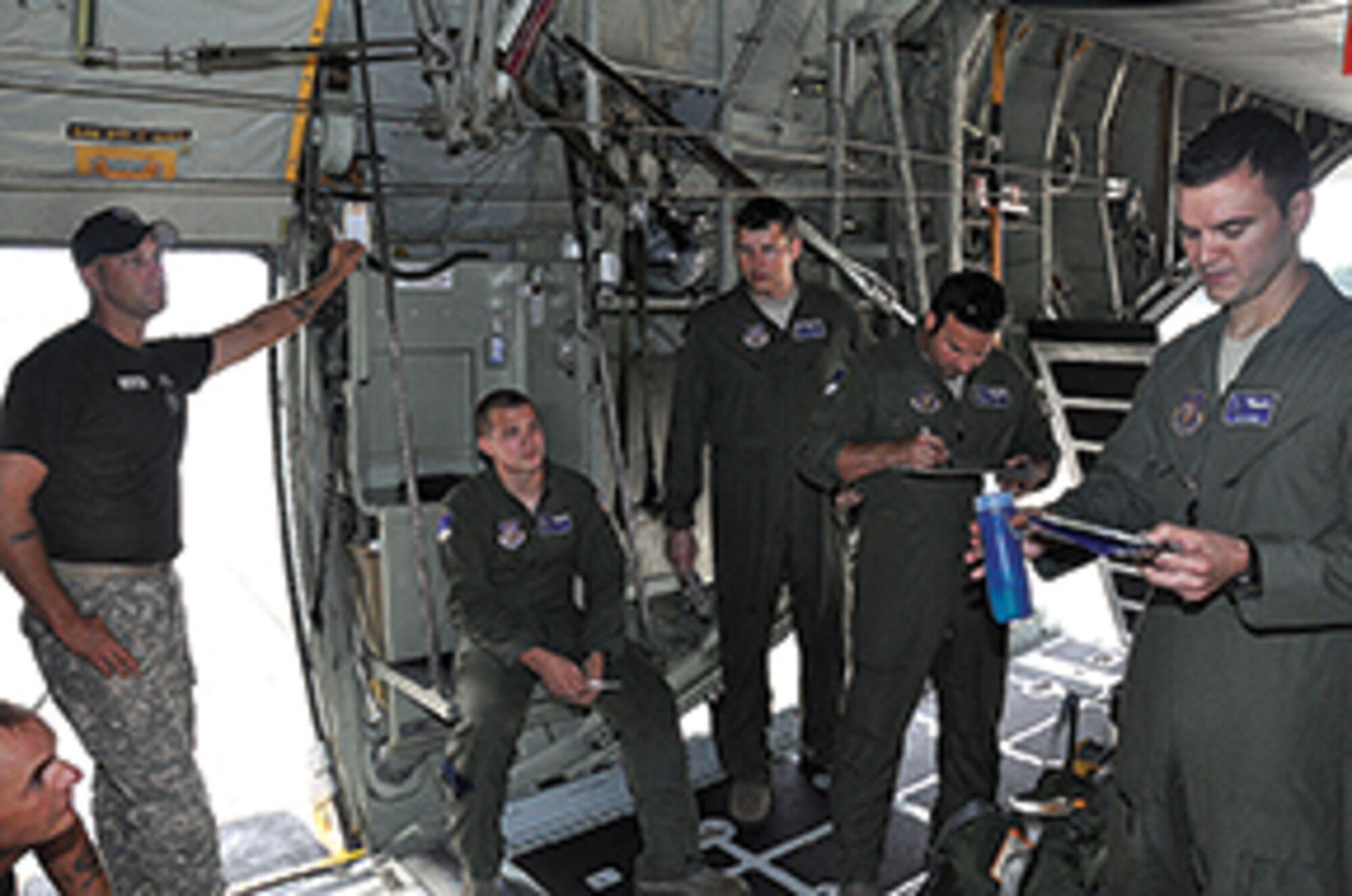 Mission Commander Capt. Don Huber, right, briefs aircrew on the coming airdrop mission while airborne instructors look on.