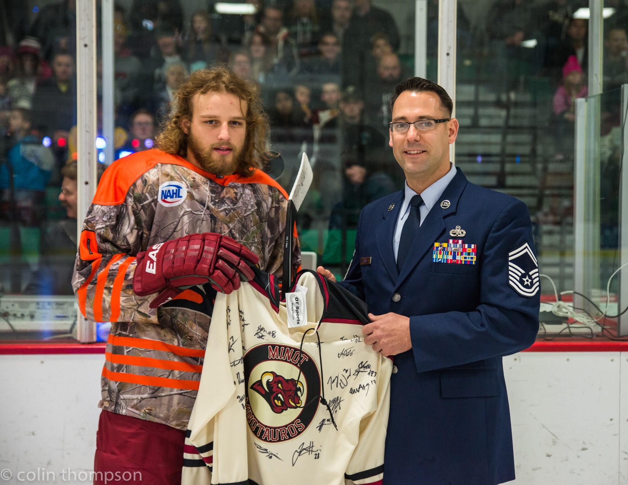 Senior Master Sgt. John Lium, 5th Aircraft Maintenance Squadron sortie support superintendent, poses for a photo with Jon Lizotte of the Minot Minotauros during a hockey game in Minot, N.D., Nov. 11, 2014. The teams let Lium drop the puck to honor him for his upcoming retirement and to thank him for his volunteer work with the team. He has been crucial in helping the team's volunteer program over the last two seasons. (Courtesy photo) 