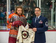 Senior Master Sgt. John Lium, 5th Aircraft Maintenance Squadron sortie support superintendent, poses for a photo with Jon Lizotte of the Minot Minotauros during a hockey game in Minot, N.D., Nov. 11, 2014. The teams let Lium drop the puck to honor him for his upcoming retirement and to thank him for his volunteer work with the team. He has been crucial in helping the team's volunteer program over the last two seasons. (Courtesy photo) 
