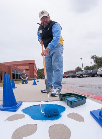 Employees from Space and Naval Warfare Systems Center Atlantic take part in the United Way Day of Caring, Nov. 14, 2014, by donating their time to paint tiger paws all over the North Charleston High School Campus to raise the schools esprit de corps in North Charleston, S.C. Hundreds of Joint Base Charleston Sailors, Airmen and civilians participated in the United Way Day of Caring, which provides an opportunity for volunteer teams to partner with local agencies and schools to increase community engagement.  (U.S. Navy photo/Joe Bullinger)