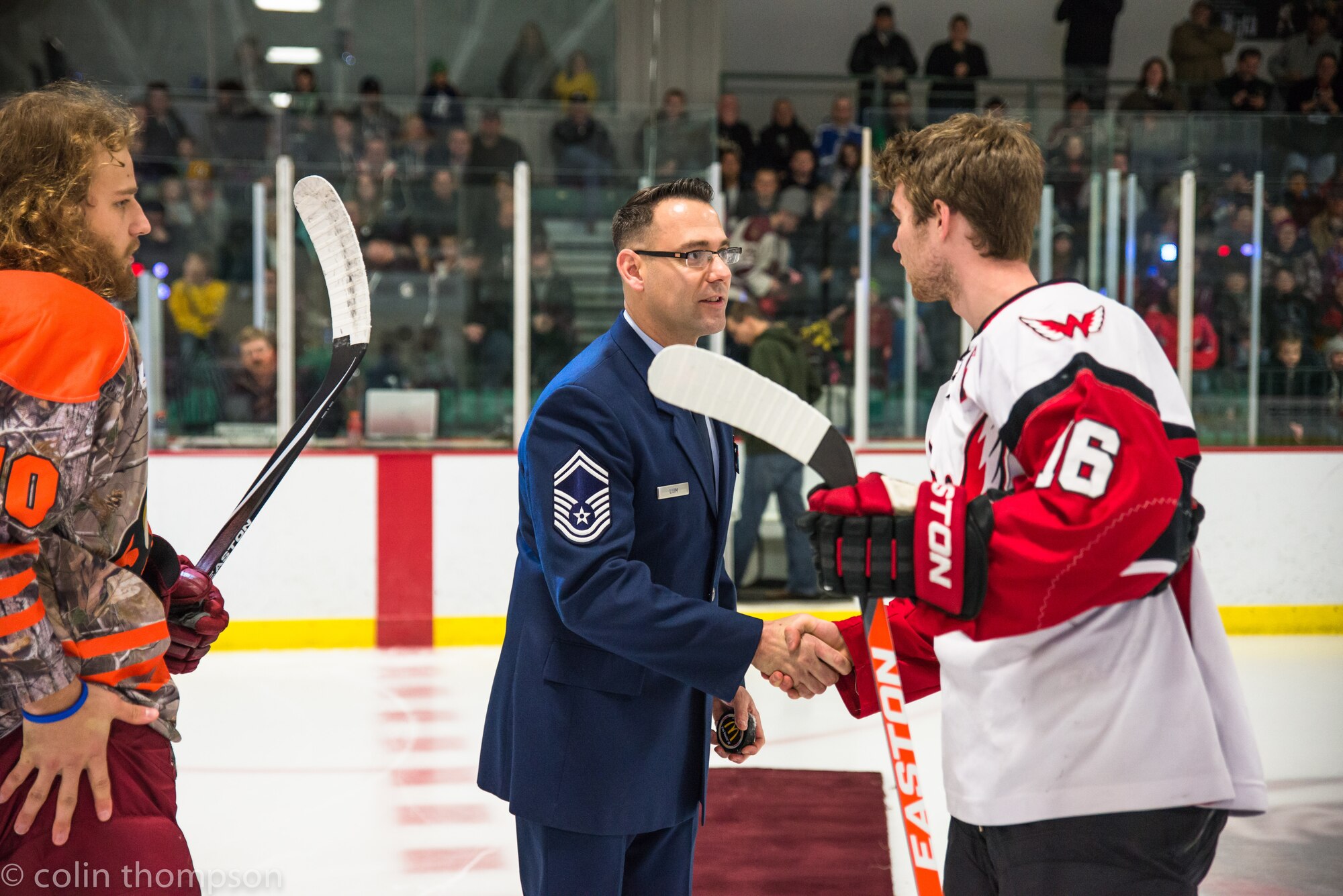 Senior Master Sgt. John Lium, 5th Aircraft Maintenance Squadron sortie support superintendent, shakes hands with Kyle Haak of the Aberdeen Wings during a hockey game in Minot, N.D., Nov. 11, 2014. The teams let Lium drop the puck to honor him for his upcoming retirement and to thank him for his volunteer work with the team. (Courtesy photo) 