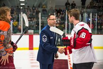 Senior Master Sgt. John Lium, 5th Aircraft Maintenance Squadron sortie support superintendent, shakes hands with Kyle Haak of the Aberdeen Wings during a hockey game in Minot, N.D., Nov. 11, 2014. The teams let Lium drop the puck to honor him for his upcoming retirement and to thank him for his volunteer work with the team. (Courtesy photo) 