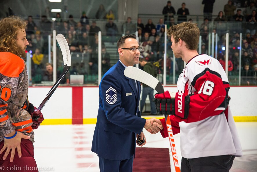 Senior Master Sgt. John Lium, 5th Aircraft Maintenance Squadron sortie support superintendent, shakes hands with Kyle Haak of the Aberdeen Wings during a hockey game in Minot, N.D., Nov. 11, 2014. The teams let Lium drop the puck to honor him for his upcoming retirement and to thank him for his volunteer work with the team. (Courtesy photo) 