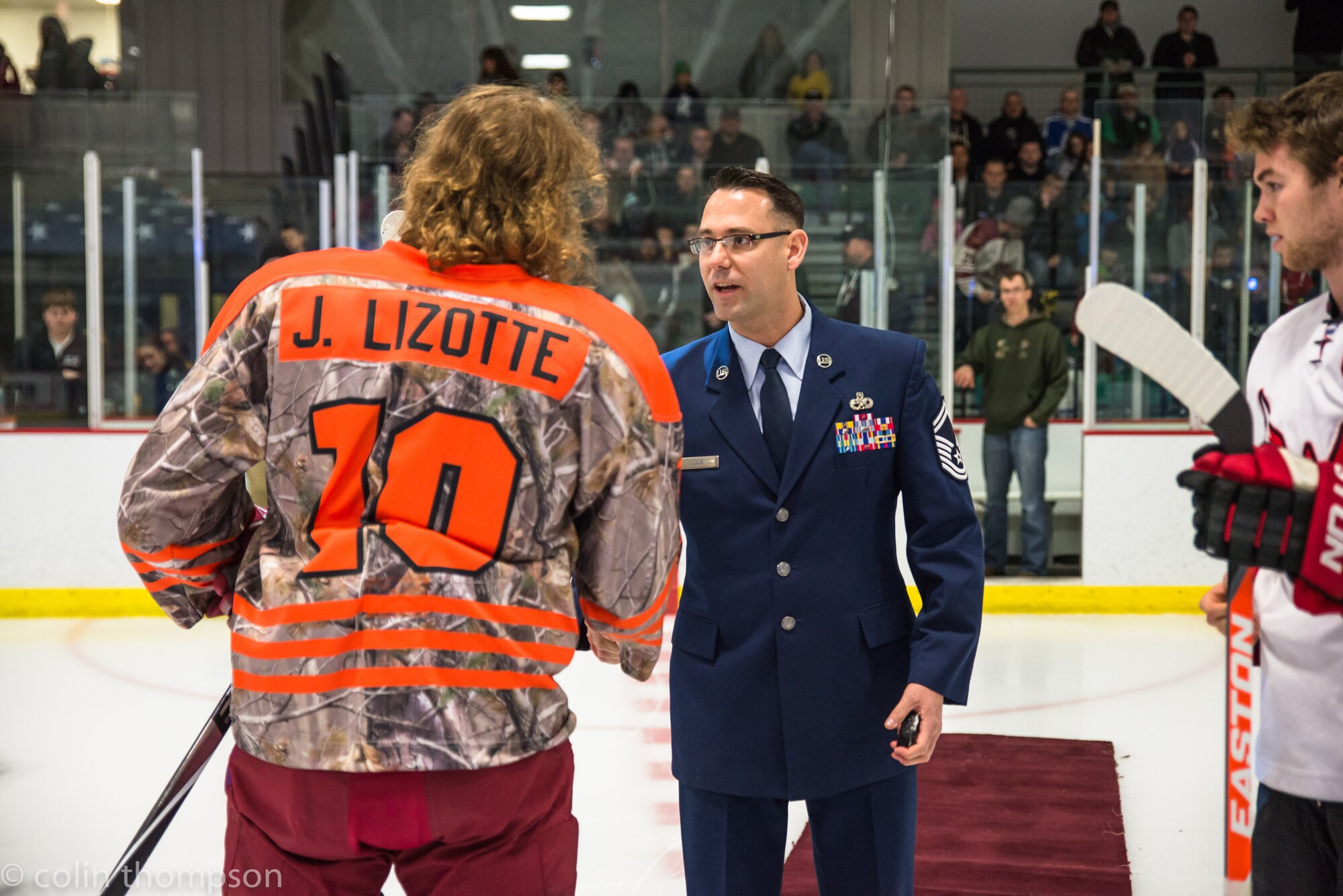 Senior Master Sgt. John Lium, 5th Aircraft Maintenance Squadron sortie support superintendent, shakes hands with Jon Lizotte of the Minot Minotauros during a hockey game in Minot, N.D., Nov. 11, 2014. The teams let Lium drop the puck to honor him for his upcoming retirement and to thank him for his volunteer work with the team. (Courtesy photo) 