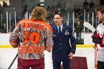Senior Master Sgt. John Lium, 5th Aircraft Maintenance Squadron sortie support superintendent, shakes hands with Jon Lizotte of the Minot Minotauros during a hockey game in Minot, N.D., Nov. 11, 2014. The teams let Lium drop the puck to honor him for his upcoming retirement and to thank him for his volunteer work with the team. (Courtesy photo) 