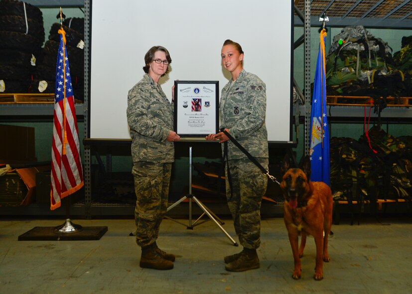 Col. Donna Pike, 436th Mission Support Group commander, presents Senior Airman Ashley Beattie, 436th Security Forces Squadron military working dog handler, with Renzo’s, 436th SFS MWD, discharge certificate during his retirement ceremony Nov. 10, 2014, at Dover Air Force Base, Del. Beattie was Renzo’s last assigned handler before being adopted by former 436th SFS MWD handler, Staff Sgt. Tatiana Carbocci. (U.S. Air Force photo/Airman 1st Class William Johnson)