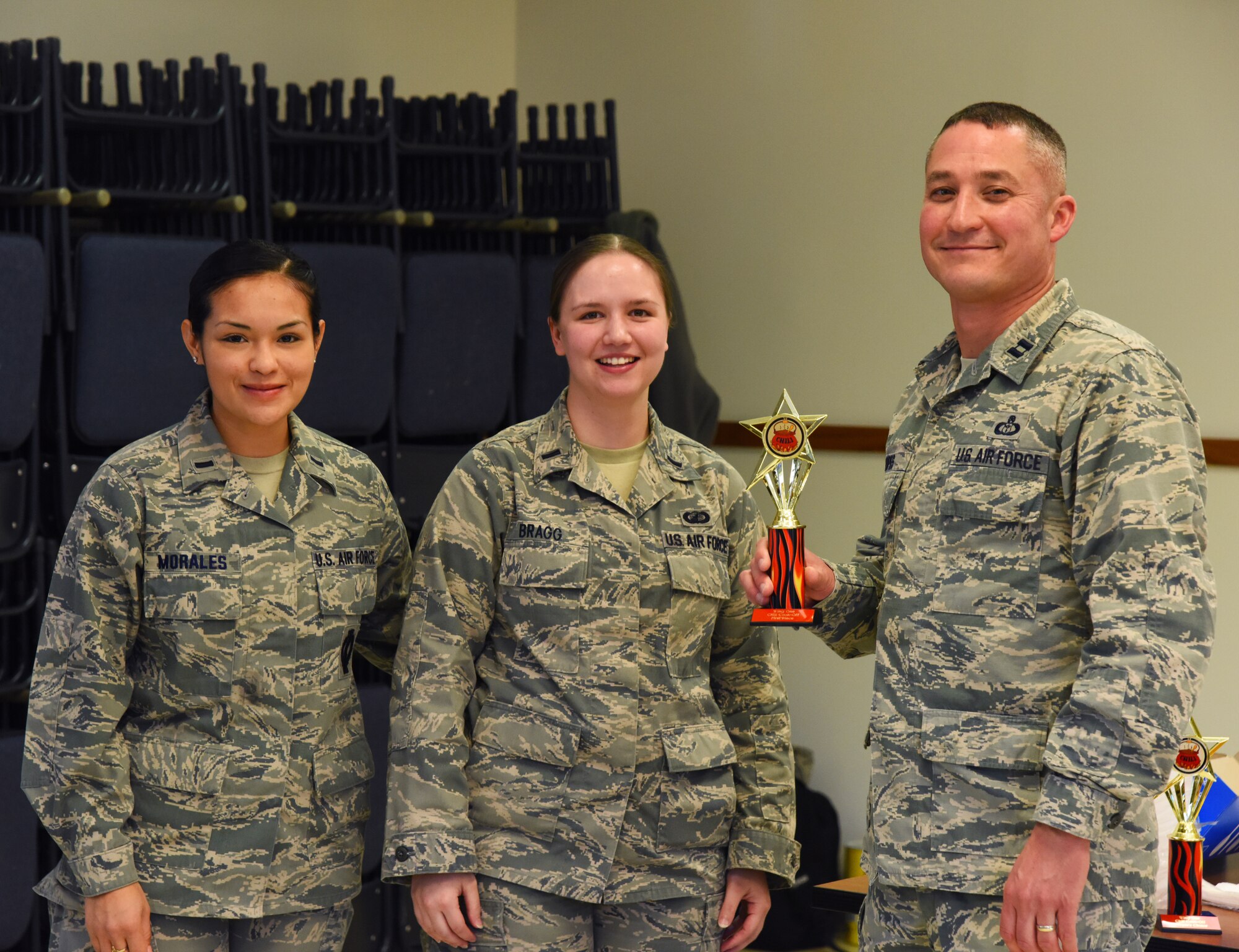 1st Lt. Mayrem Morales, 10th Missile Squadron deputy combat missile crew commander (left), and 1st Lt. Amy Bragg, 341st Comptroller Squadron deputy budget officer (center), stand with Capt. Richard Lopes, 341st Operations Support Squadron weather flight commander, after Lopes took first place in wing one’s chili cook off event Nov. 17. After the cook off, donations from participants were given to various organizations of the Combined Federal Campaign organization. (U.S. Air Force photo/ Airman 1st Class Collin Schmidt)