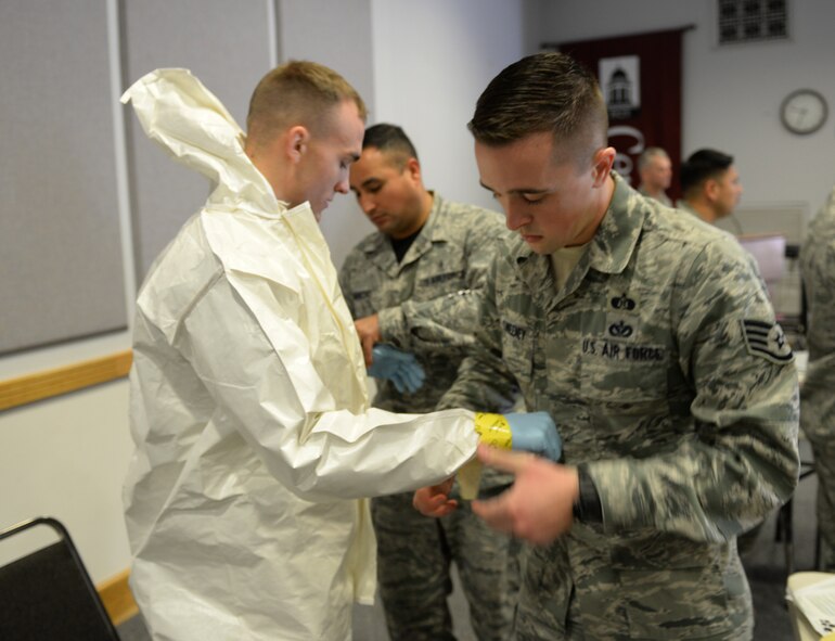 Staff Sgt. Charles Sweeney, 2nd Civil Engineer Squadron emergency management, tapes personal protective equipment for Senior Airman Brian Foley, 2nd Civil Engineer Squadron emergency management, during an Ebola training exercise at Centenary College of Louisiana in Shreveport, La., Nov. 14, 2014. While Ebola was the genesis for the training, event organizers and participants discussed past health threats such as AIDS, SARS, anthrax and influenza and reflected on how important it is to be prepared and approach the issue with a team mentality. (U.S. Air Force photo/Airman 1st Class Curt Beach)