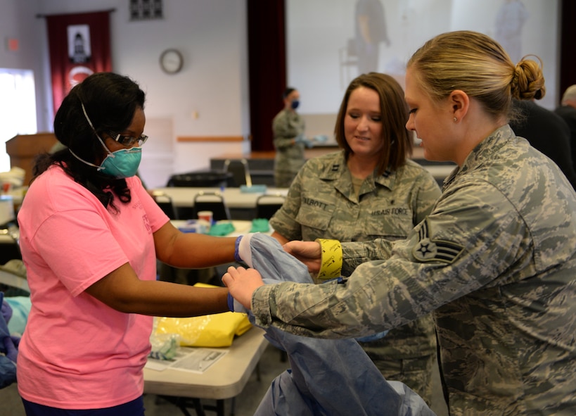 Capt. Julianne Talbot, 2nd Medical Operations Squadron clinical nurse and infection control officer, and Senior Airman Alycia Provenzo, 2nd Aerospace Medical Squadron bioenvironmental engineering technician, help local medical personnel properly remove personal protective equipment at Centenary College of Louisiana in Shreveport, La., Nov. 14, 2014. Barksdale Airmen led the training in order to pre-emptively strengthen coordination efforts and increase awareness of proper procedures in the event they are needed. (U.S. Air Force photo/Airman 1st Class Curt Beach)