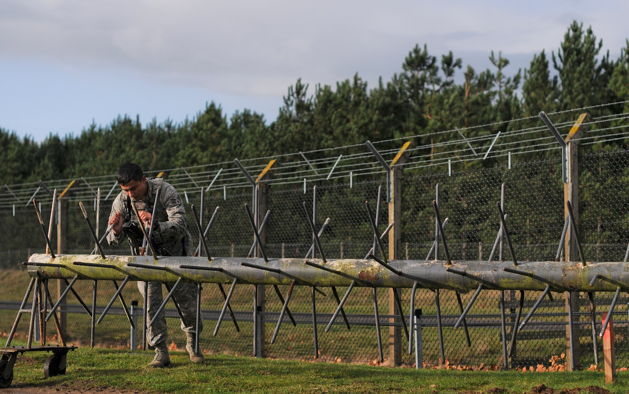 Senior Airman Manuel Garcia, 48th Security Forces Squadron response force leader, moves a barrier away from a gate, creating a vehicle passageway at Royal Air Force Lakenheath, England, Nov. 12, 2014. Security forces members follow procedural checklists as they patrol sensitive areas and ensure base assets are protected at all times. (U.S. Air Force photo by Senior Airman Erin O’Shea/Released) 