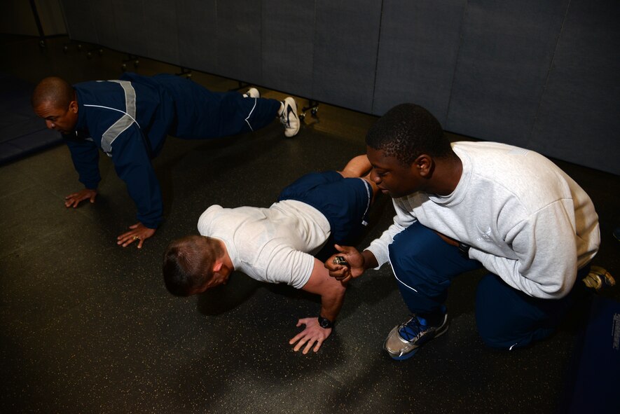 (From right) U.S. Air Force Airman 1st Class James Haydel, 609th Air and Space Operations Center Detachment 1 air tasking order technician, observes and counts for Airman 1st Class Dylan Gadbois, 20th Medical Operations Squadron medical technician, while he accomplishes the push-up portion of his Air Force physical training test at Shaw Air Force Base, S.C., Nov. 18, 2014. The Air Force PT test is performed semi-annually, unless the Airman achieves a score of 90 percent or above, then it is accomplished annually. (U.S. Air Force photo by Airman 1st Class Jonathan Bass/Released)