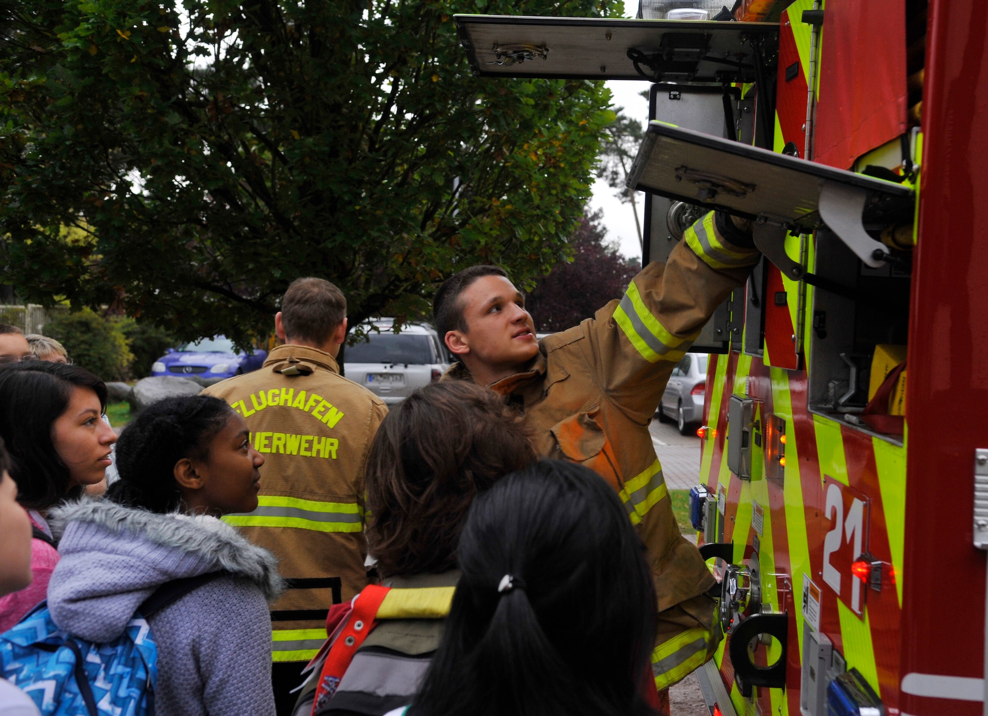 Airman 1st Class Jacob Frost, 86th Civil Engineer Squadron Fire Department firefighter, opens hatches on the back of a fire truck to teach Ramstein Middle School students about the equipment they use during training and real-world situations on Oct. 9, 2014 at Ramstein Air Base, Germany. The students had the chance to ask the 86th CES firefighters questions and sit in the front seat of the fire truck. (U.S. Air Force photo/Airman Larissa Greatwood)
