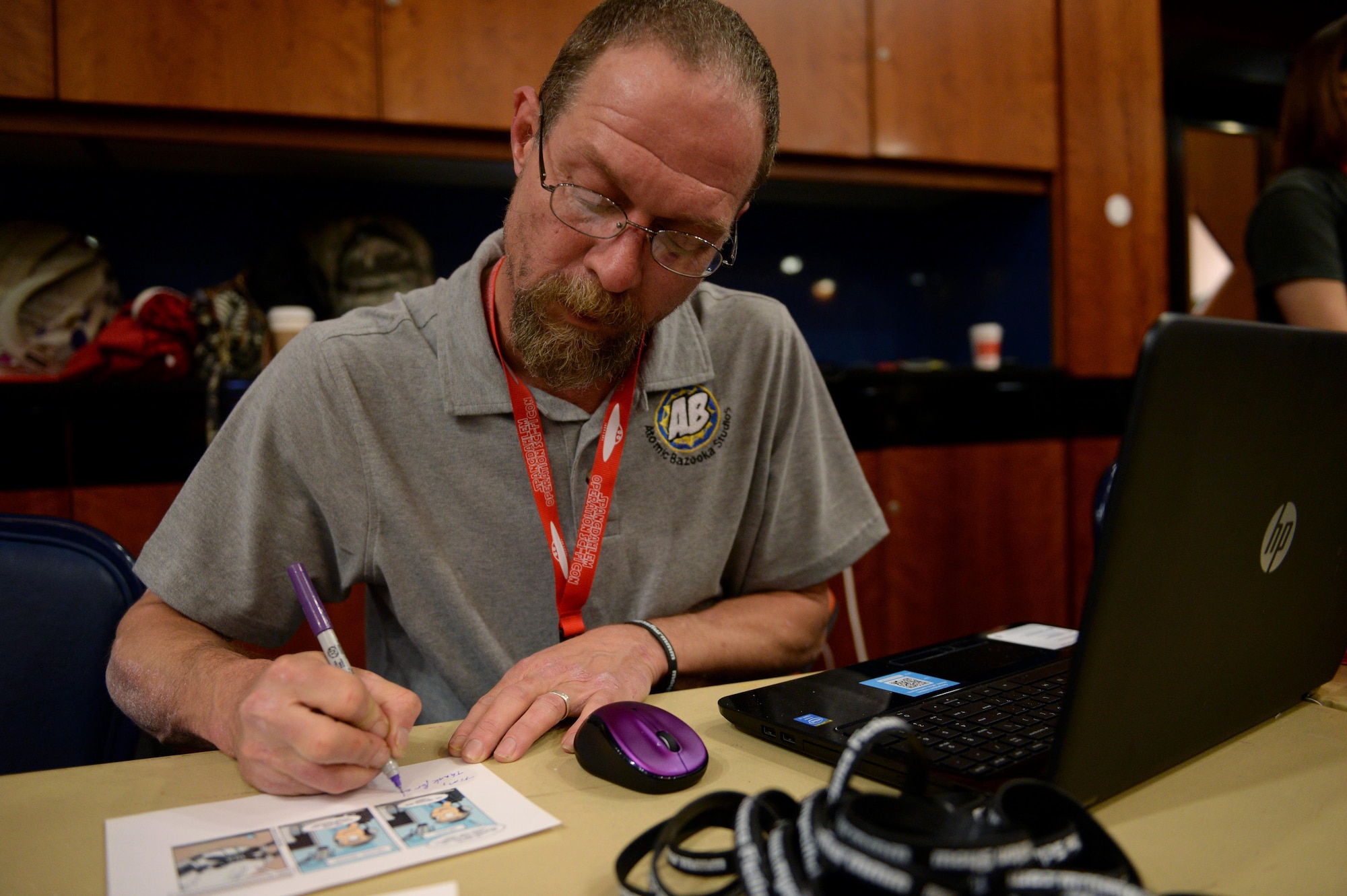Keith Houin, co-owner and creator of Atomic Bazooka Studios, autographs a comic strip during Operation Sci-Fi Con 2015 in the Landscheid Room at Club Eifel on Spangdahlem Air Base, Germany, Nov. 15, 2014. Houin founded the company after retiring from the U.S. Air Force as a master sergeant in Public Affairs. (U.S. Air Force photo by Airman 1st Class Timothy Kim/Released)