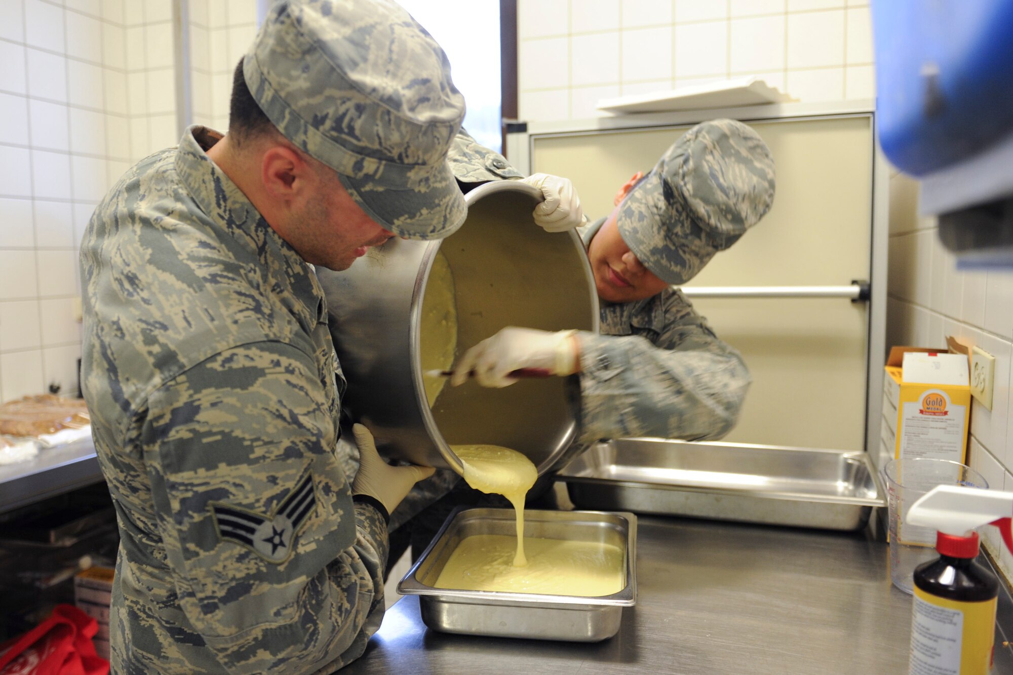 Senior Airman Jonathan DaSilva, 786th Force Support Squadron food service journeyman, and Airman First Class Jalyssa Holman, 786th FSS server apprentice, pour cake batter into a container in the Rhineland Inn Dining Facility on Ramstein Air Base, Germany, Oct. 8, 2014. The Rhineland Inn Dining Facility has staff on shift 24 hours a day to ensure food is ready for the Airmen they are serving throughout the day. (U.S. Air Force photo/Airman 1st Class Michael Stuart)