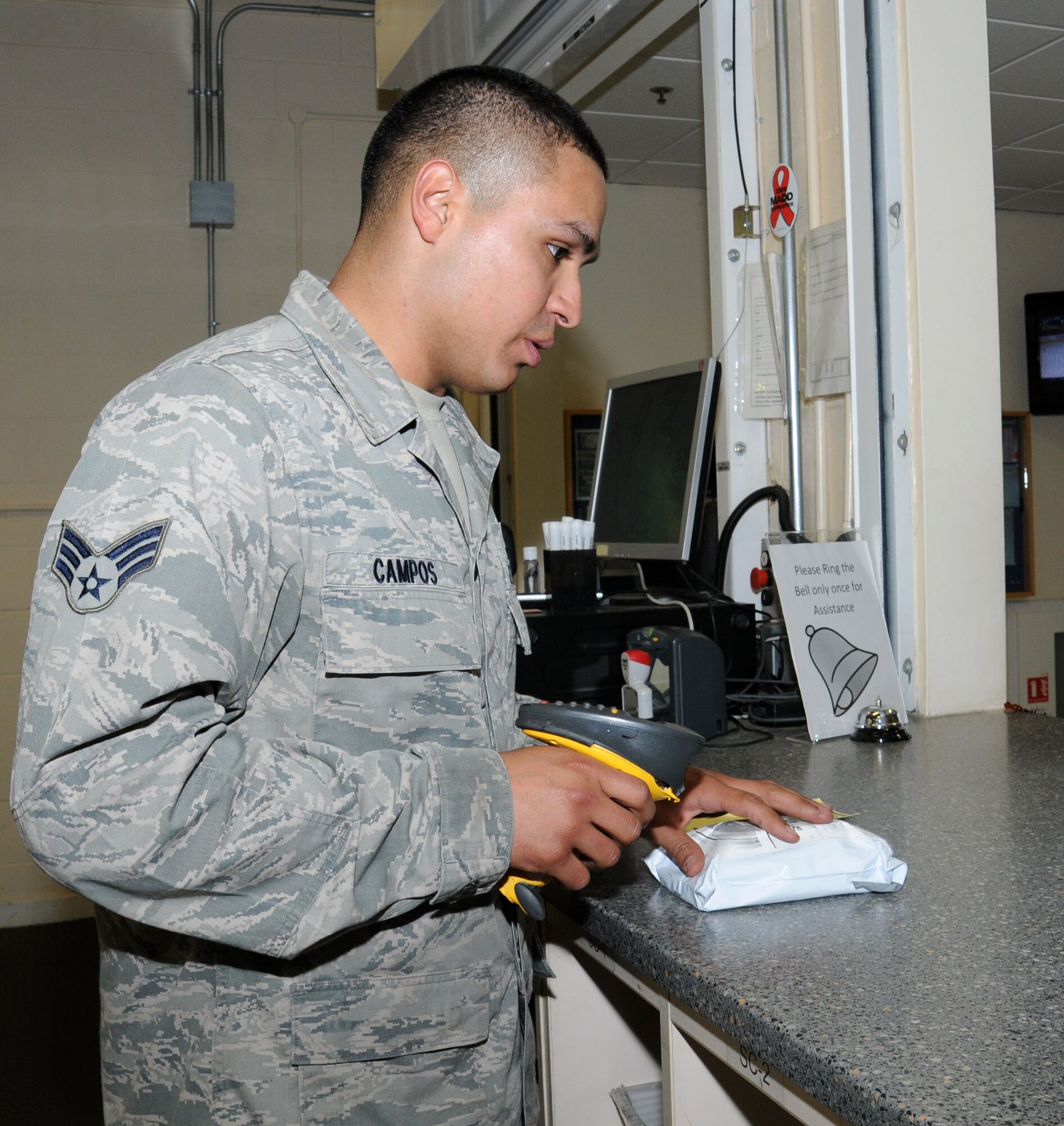 U.S. Air Force Senior Airman Oscar Campos-Ortiz, 100th Communications Squadron postal clerk from Dallas, scans the barcode of a package before handing it to the customer Oct. 24, 2014, on RAF Mildenhall, England. The scanner keeps track of all packages with tracking numbers and sends updates to a website so customers know exactly where their mail is. (U.S. Air Force photo by Gina Randall/Released)