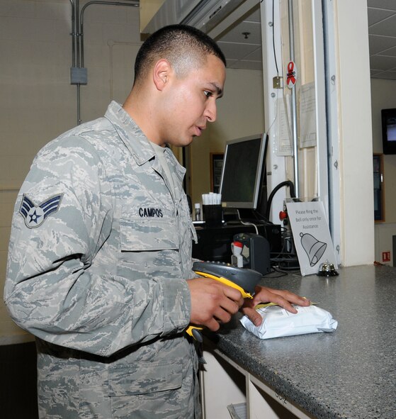 U.S. Air Force Senior Airman Oscar Campos-Ortiz, 100th Communications Squadron postal clerk from Dallas, scans the barcode of a package before handing it to the customer Oct. 24, 2014, on RAF Mildenhall, England. The scanner keeps track of all packages with tracking numbers and sends updates to a website so customers know exactly where their mail is. (U.S. Air Force photo by Gina Randall/Released)