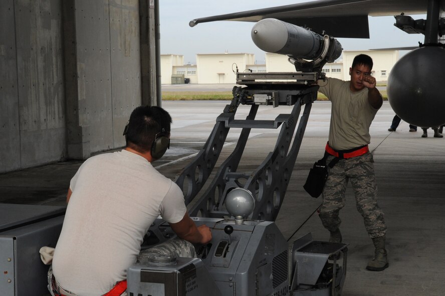 U.S. Air Force Senior Airman Chinh Nguyen, 18th Aircraft Maintenance Squadron weapons load crew member, drives the MJ-1 Jammer, a missile mover, while Staff Sgt. Paolo Santos, 18th AMXS weapons load crew chief, helps him navigate into place during the quarterly weapons loading competition at Kadena Air Base, Japan, Nov. 17, 2014. The competition tests the team's ability to load weapons on F-15C Eagles in a fast and safe manner. This competition was held between the 44th and 67th Aircraft Maintenance Units of the 18th AMXS. (U.S. Air Force photo by Airman 1st Class Zackary A. Henry/Released)