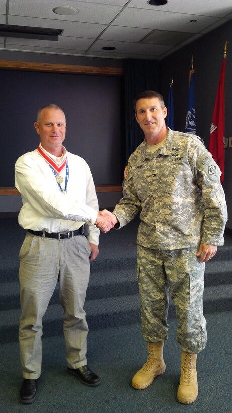 The Tulsa District Commander, Col. Richard A. Pratt, shakes hands with Wade Anderson, director of the Southwestern Division Dam Safety Production center, after presenting him with a bronze de Fleury medal.