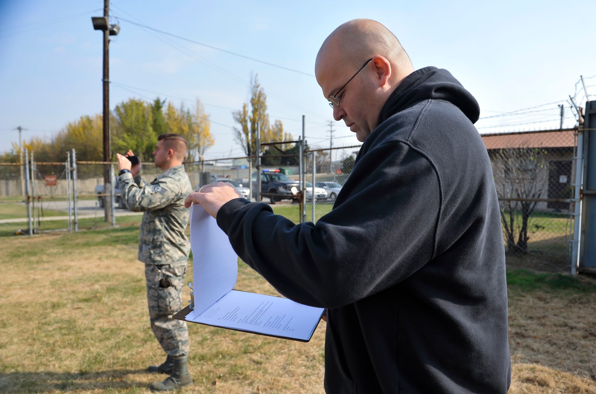 Master Sgt. Matthew Troiano, 51st Security Forces Squadron kennel master, looks over the adoption paperwork for Fficher, 51st SFS MWD, as the unit creates an adoption video Nov. 14, 2014, on Osan Air Base, Republic of Korea. The month long adoption process begins when an MWD becomes eligible for retirement. (U.S. Air Force photo by Senior Airman David Owsianka)