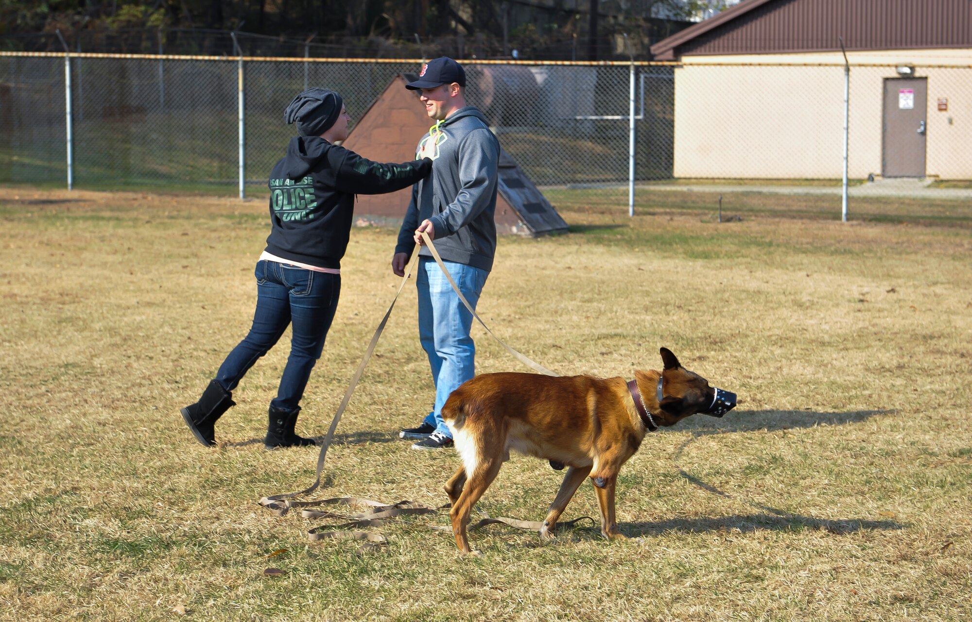 Staff Sgt. Anique Brassard pushes Senior Airman Noah Hyatt, both 51st Security Forces Squadron military working dog handlers, as the unit takes a video during part of the adoption process Nov. 14, 2014, on Osan Air Base, Republic of Korea. The video is created to show that the dog has no tendencies to aggress and it suitable for pet adoption. (U.S. Air Force photo by Senior Airman David Owsianka)