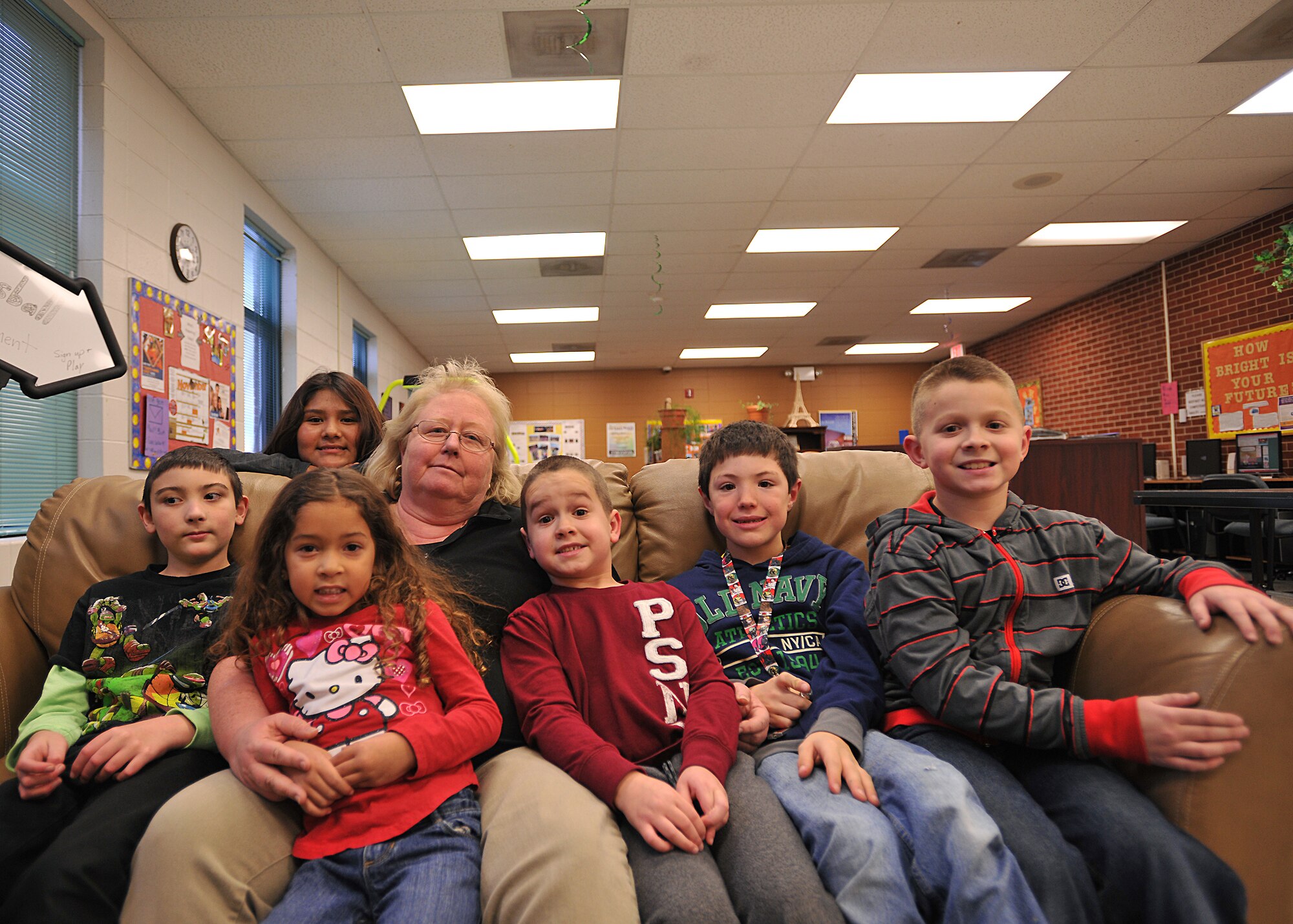 Peggy Howard, 319th Force Support Squadron school age program coordinator, sits on the couch with children from the Youth Center on Grand Forks Air Force Base, N.D., Nov. 6, 2014. Howard was named the 319th Air Base Wing Warrior of the Week for the third week of November 2014. (U.S. Air Force photo/Senior Airman Xavier Navarro)