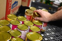 Canned goods are stacked by Senior Airman Jonathan Yang, 28th Operations Support Squadron airfield management technician, to be included in Thanksgiving meal baskets as part of Operation Warmheart at Ellsworth Air Force Base, S.D., Nov. 16, 2014. This year, 170 baskets of donated food were assembled and delivered to Airmen who would not be able to afford holiday meals otherwise. (U.S. Air Force photo by Senior Airman Zachary Hada/Released)
