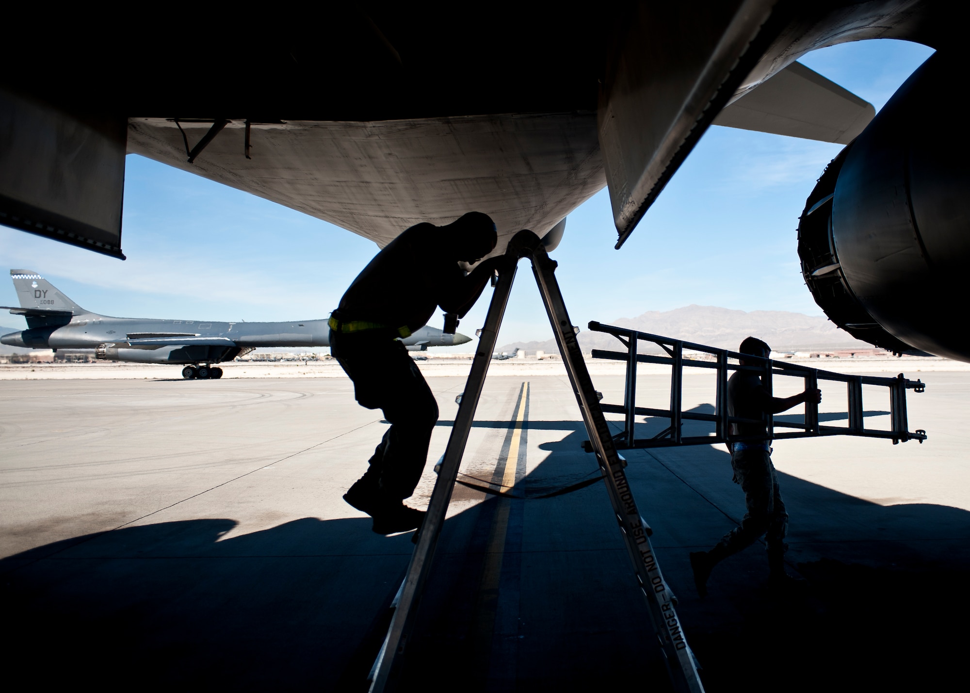 Two crew chiefs from the 34th Aircraft Maintenance Unit, Ellsworth Air Force Base, S.D., perform maintenance on a B-1B Lancer assigned to the 34th Bomb Squadron, Ellsworth AFB, during Green Flag-West 15-02 at Nellis AFB, Nev., Nov. 18, 2014. Green Flag-West is a close air support exercise and ensures the highest level of integration between air and ground forces, and is administered by the U.S. Air Force Warfare Center and Nellis AFB through the 549th Combat Training Squadron. (U.S. Air Force photo by Staff Sgt. Siuta B. Ika)