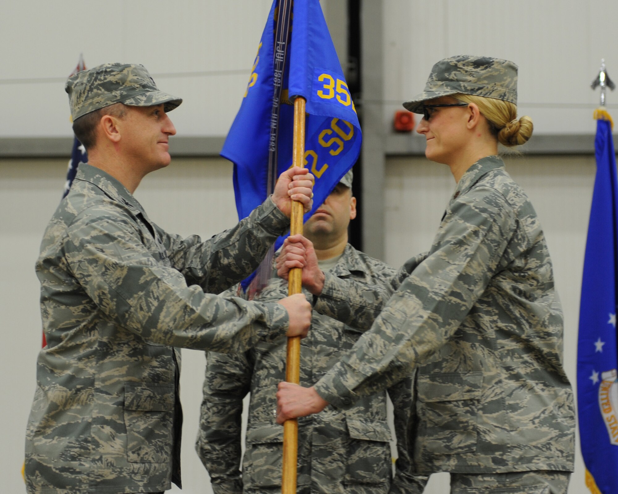 U.S. Air Force Col. Nathan Green, left, 352nd Special Operations Group commander, passes the 352nd SOMXS guidon to U.S. Air Force Maj. Seanna Less, 352nd Special Operations Maintenance Squadron commander, during the 352nd SOMXS change of command Nov. 19, 2014, in Hanger 803 at RAF Mildenhall, England. The 352nd SOMXS is the largest U.S. Air Force squadron in Europe. (U.S. Air Force photo by Airman 1st Class Preston Webb/Released)