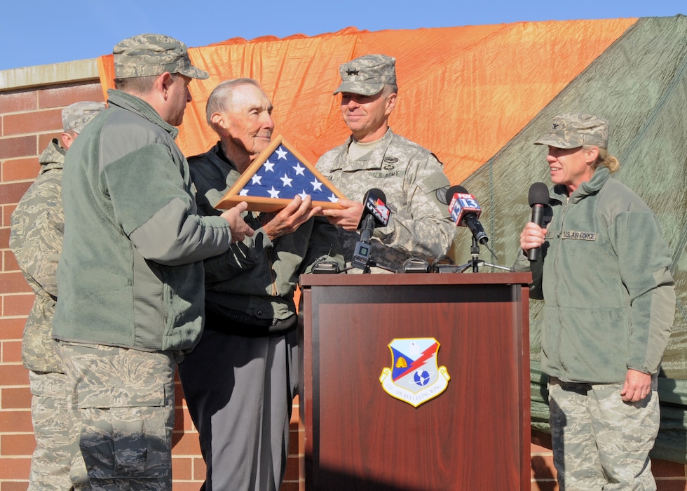 Maj. Gen. Jefferson Burton, Adjutant General of the Utah National Guard, presents a flag to retired Air Force Brig. Gen. Roland R. Wright during a ceremony to rename the Utah Air National Guard Base in his honor held in Salt Lake City, Utah on Nov. 18, 2014. The flag was flown over the Roland R. Wright Air National Guard base, as well as on a KC-135 Stratotanker mission. Wright, a combat pilot with a distinguished military career spanning more than three decades, served as Utah's first Chief of Staff for Air. (Air National Guard photo by Staff Sgt. Annie Edwards/RELEASED)