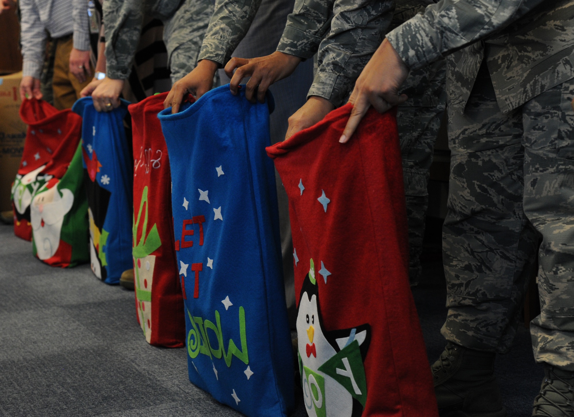 Bags stand partially filled at Airmen’s feet during the Air Force District of Washington’s 18th care package packing event at Joint Base Andrews, Md., Nov. 17, 2014. Individuals from the unit along with local businesses, churches, schools, and people connected to AFDW from across the country donated snacks, beverage mixes, and more for the packages. (U.S. Air Force photo/Tech. Sgt. Tammie Moore)