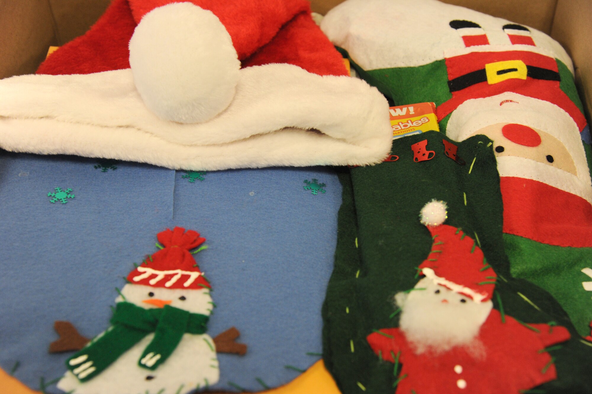 Homemade Christmas tree skirts and stockings sit at the top of care packages packed by Air Force District of Washington Airmen during the command’s 18th care package packing event at Joint Base Andrews, Md., Nov. 17, 2014. The Airmen packed 25 care packages with more than 90 items each destine for nine different countries. Home economics students from Theodore G. Davis Middle School in Waldorf, Md...., made the Christmas tree skirts and stockings in the care packages. In addition, students from Theodore G. Davis Middle School and Mattawoman Middle School, also in Waldorf, and Girl Scout Troop 5329 from Marion, Iowa, wrote more than 1,000 cards and letters which were included in the care packages. Students from these middle schools have donated items for the quarterly AFDW care packages since 2011. (U.S. Air Force photo/Master Sgt. Tammie Moore) 