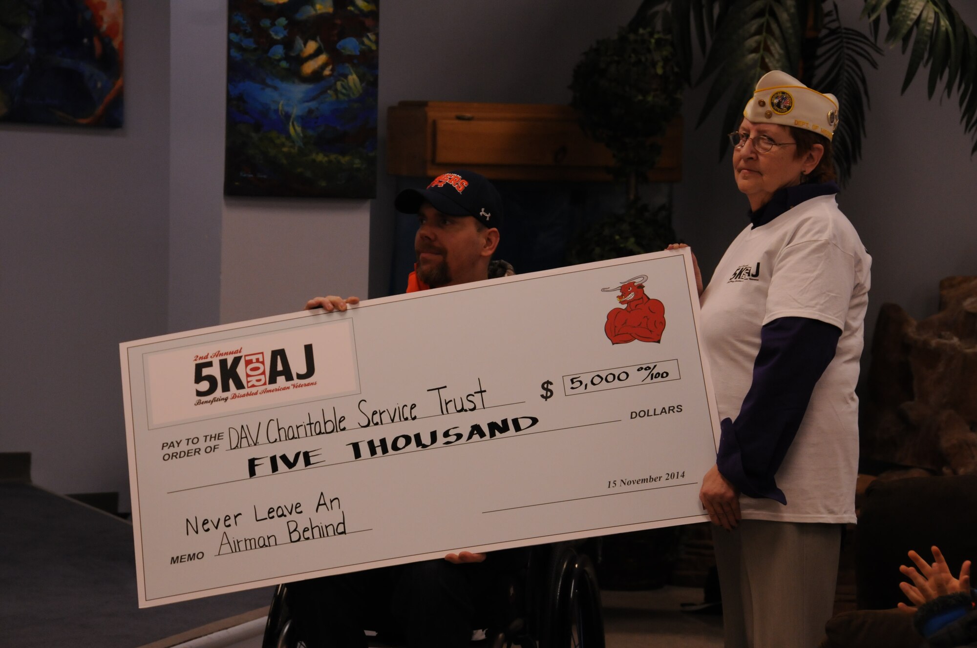 Retired Master Sgt. Albert “AJ” Jackson and Silva E. Royer, Disabled American Veterans Department of Mississippi commander, accept a donation check at the second annual 5K for AJ Nov. 15, 2014, at the Levitow Training Support Facility, Keesler Air Force Base, Miss. The event raised more than $5,000 for the Disabled American Veterans charity and drew approximately 300 participants. (U.S. Air Force photo by Airman 1st Class Duncan McElroy/Released)