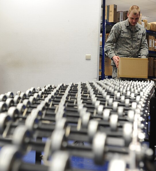 Staff Sgt. Chris Breidigan, 86th Communications Squadron postal specialist, places a package on the conveyor belt after a costumer drops it off for shipment March 27, 2014, at Ramstein Air Base, Germany. The 78 members of the North Side Post Office ensure packages and other mail leave and arrive at Ramstein promptly by using quality service, pride in their work and motivation.(U.S. Air Force photo/Airman 1st Class Holly Mansfield)