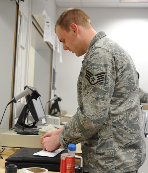 Staff Sgt. Chris Breidigan, 86th Communications Squadron postal specialist, puts a postal label on mail for a customer March 27, 2014, at Ramstein Air Base, Germany. The 78 members of the North Side Post Office ensure packages and other mail leave and arrive at Ramstein promptly by using quality service, pride in their work and motivation.(U.S. Air Force photo/Airman 1st Class Holly Mansfield)