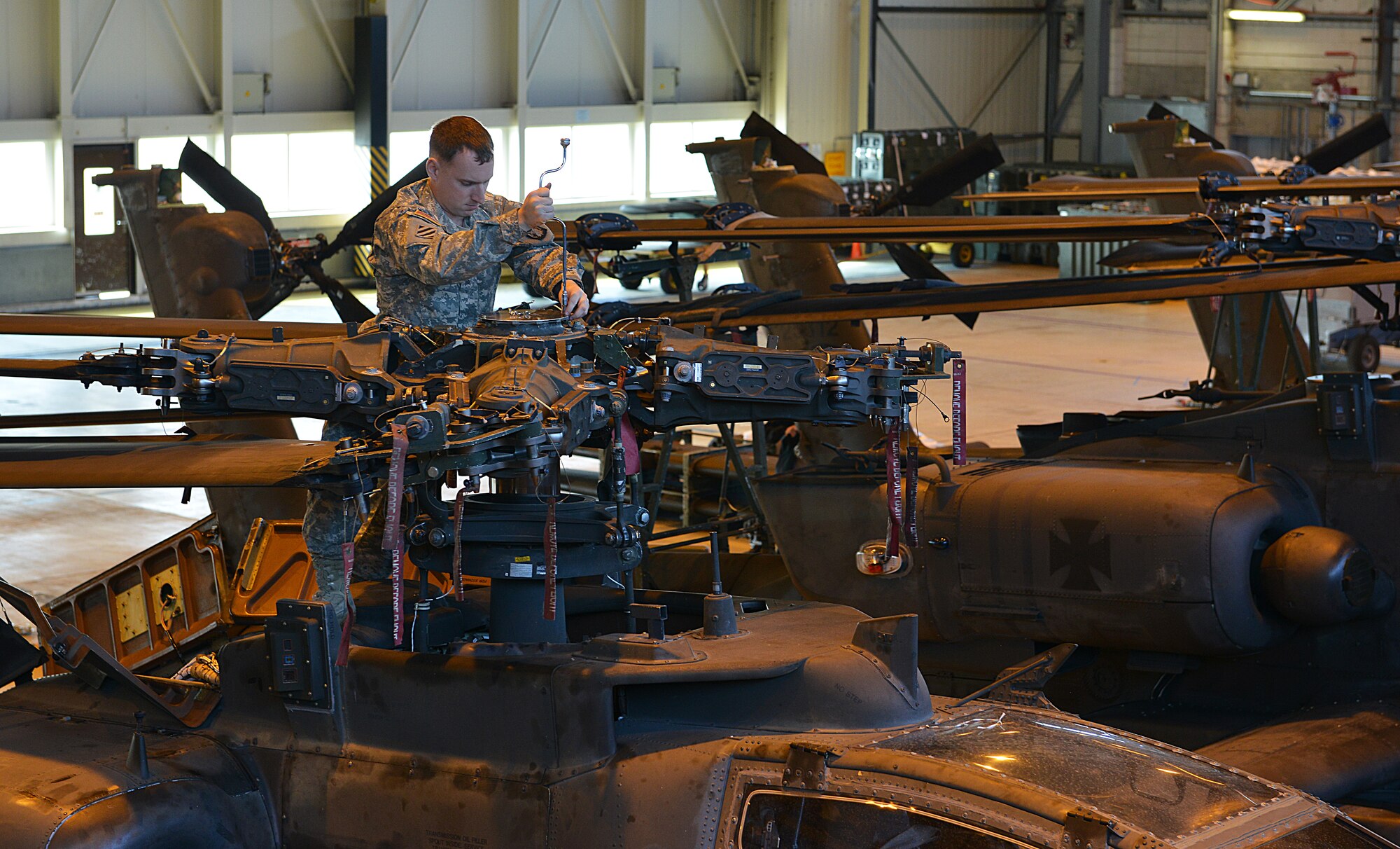 Army Staff Sgt. Richard Edge, 412th Aviation Support Battalion Bravo company AH-64D Apache Helicopter armament electrical repair mechanic, tightens bolts during a blade folding mission March 26, 2014, at Ramstein Air Base, Germany. An eight-man team of soldiers visited Ramstein to repair and mobilize eight Apache attack helicopters from illeshei, Germany. The ten-day assignment began on March 18 and was completed March 28. The mission consisted of inspections and equipment checks before being loaded up and shipped back to a deployed location in a C-17 Globe Master III. The mission allowed them to work alongside Air Force members in a joint effort to prepare the Apaches for operations down-range. (U.S. Air Force photo/Airman Dymekre Allen)  