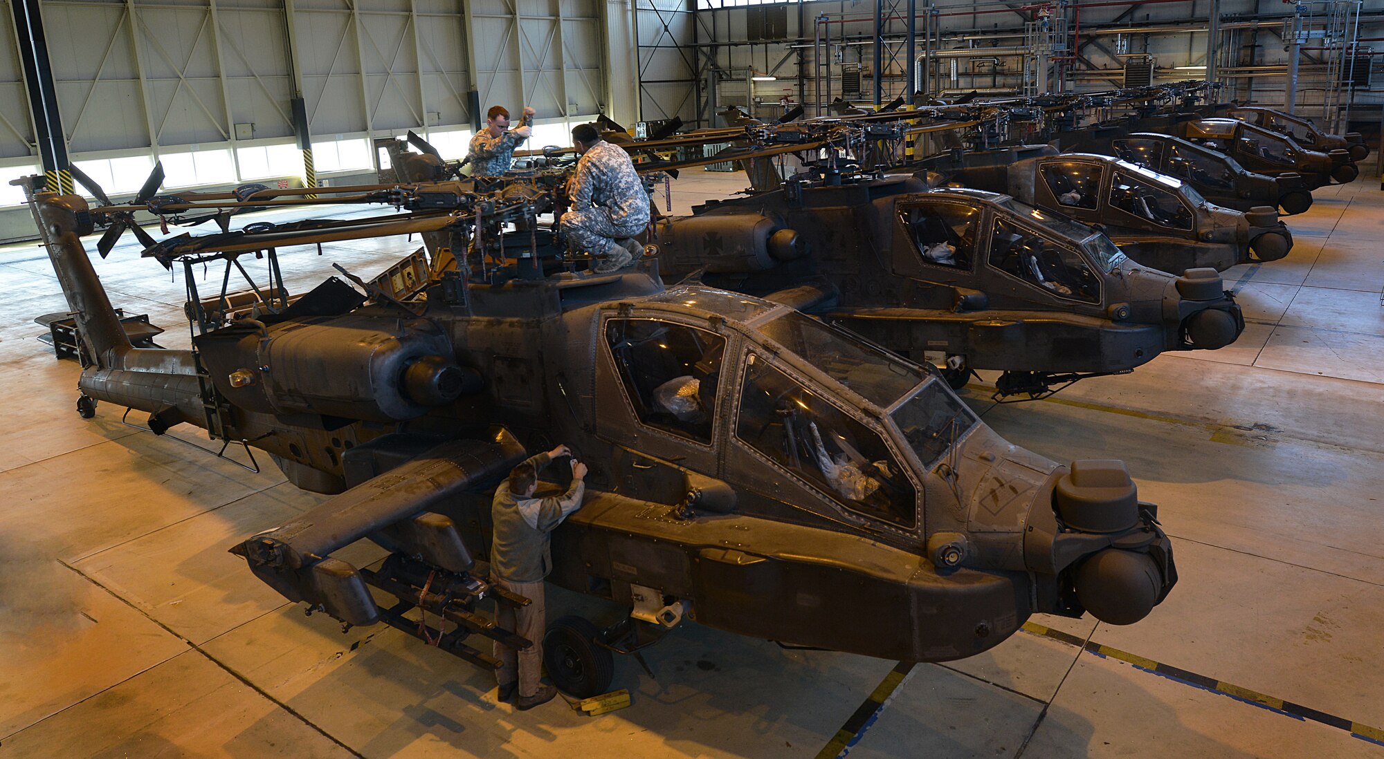 Army Staff Sgt. Ray Trevino (right) and Army Staff Sgt. Richard Edge, 412th Aviation Support Battalion Bravo company AH-64D Apache Helicopter armament electrical repair mechanic, inspect blades on an Apache during a blade folding mission March 26, 2014, at Ramstein Air Base, Germany. An eight-man team of soldiers visited Ramstein to repair and mobilize eight Apache attack helicopters from illeshei, Germany. The ten-day assignment began on March 18 and was completed March 28. The mission consisted of inspections and equipment checks before being loaded up and shipped back to a deployed location in a C-17 Globe Master III. The mission allowed them to work alongside Air Force members in a joint effort to prepare the Apaches for operations down-range. (U.S. Air Force photo/Airman Dymekre Allen)  