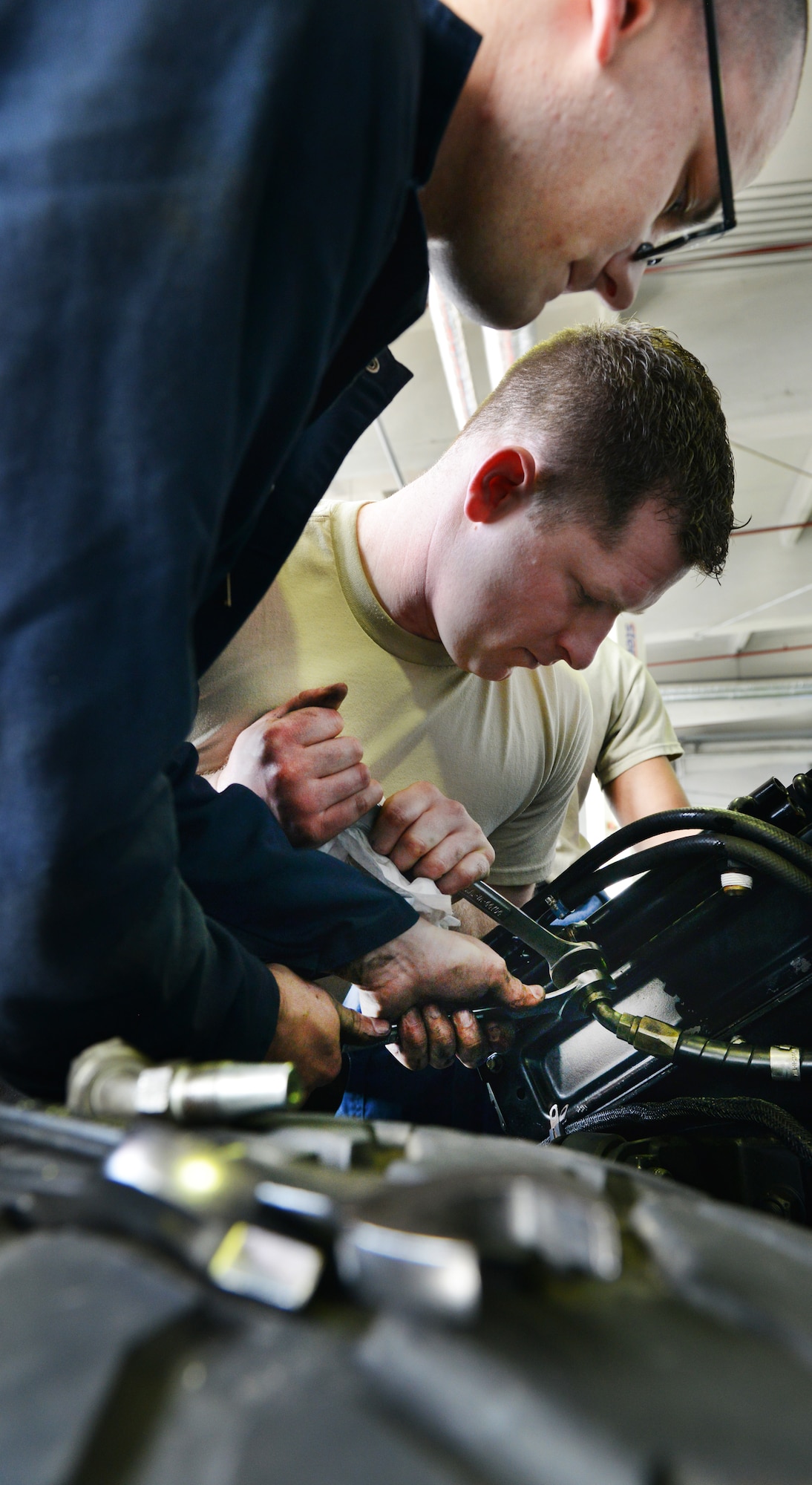 Senior Airman Brian Klockow (right) and Airman 1st Class Frederick Vogelgesang, 86th Vehical Readiness Squadron light vehical mechanics, tighten the radiator hoses of a Humvee, April 1, 2014 at Ramstein Air Base, Germany. (U.S. Air Force photo/ Airman Dymekre Allen)