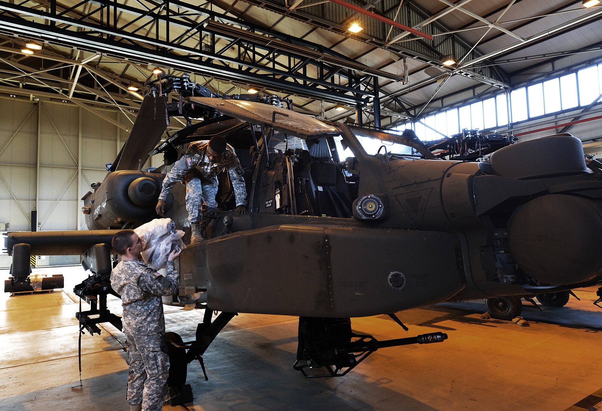 Army Pfc. Dillon Burnhauser (left) and Anfernee Shepard, 412th Aviation Support Battalion Bravo company AH-64D Apache Helicopter armament electrical repair mechanic, load repair equipment on to an Apache during a blade folding mission March 26, 2014, at Ramstein Air Base, Germany. An eight-man team of soldiers visited Ramstein to repair and mobilize eight Apache attack helicopters from illeshei, Germany. The ten-day assignment began on March 18 and was completed March 28. The mission consisted of inspections and equipment checks before being loaded up and shipped back to a deployed location in a C-17 Globe Master III. The mission allowed them to work alongside Air Force members in a joint effort to prepare the Apaches for operations down-range. (U.S. Air Force photo/Airman Dymekre Allen)  