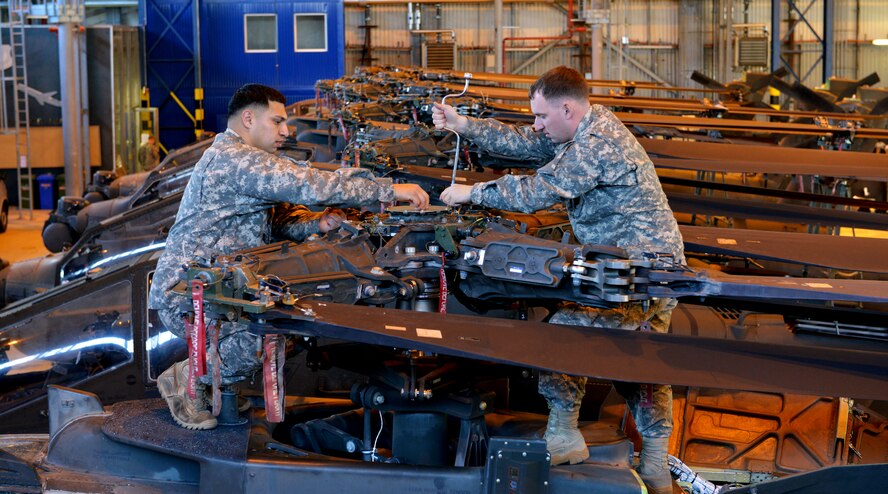 Army Staff Sgt. Ray Trevino (left) and Army Staff Sgt. Richard Edge, 412th Aviation Support Battalion Bravo company AH-64D Apache Helicopter armament electrical repair mechanic, tightens bolts during a blade folding mission March 26, 2014, at Ramstein Air Base, Germany. An eight-man team of soldiers visited Ramstein to repair and mobilize eight Apache attack helicopters from illeshei, Germany. The ten-day assignment began on March 18 and was completed March 28. The mission consisted of inspections and equipment checks before being loaded up and shipped back to a deployed location in a C-17 Globe Master III. The mission allowed them to work alongside Air Force members in a joint effort to prepare the Apaches for operations down-range. (U.S. Air Force photo/Airman Dymekre Allen)  