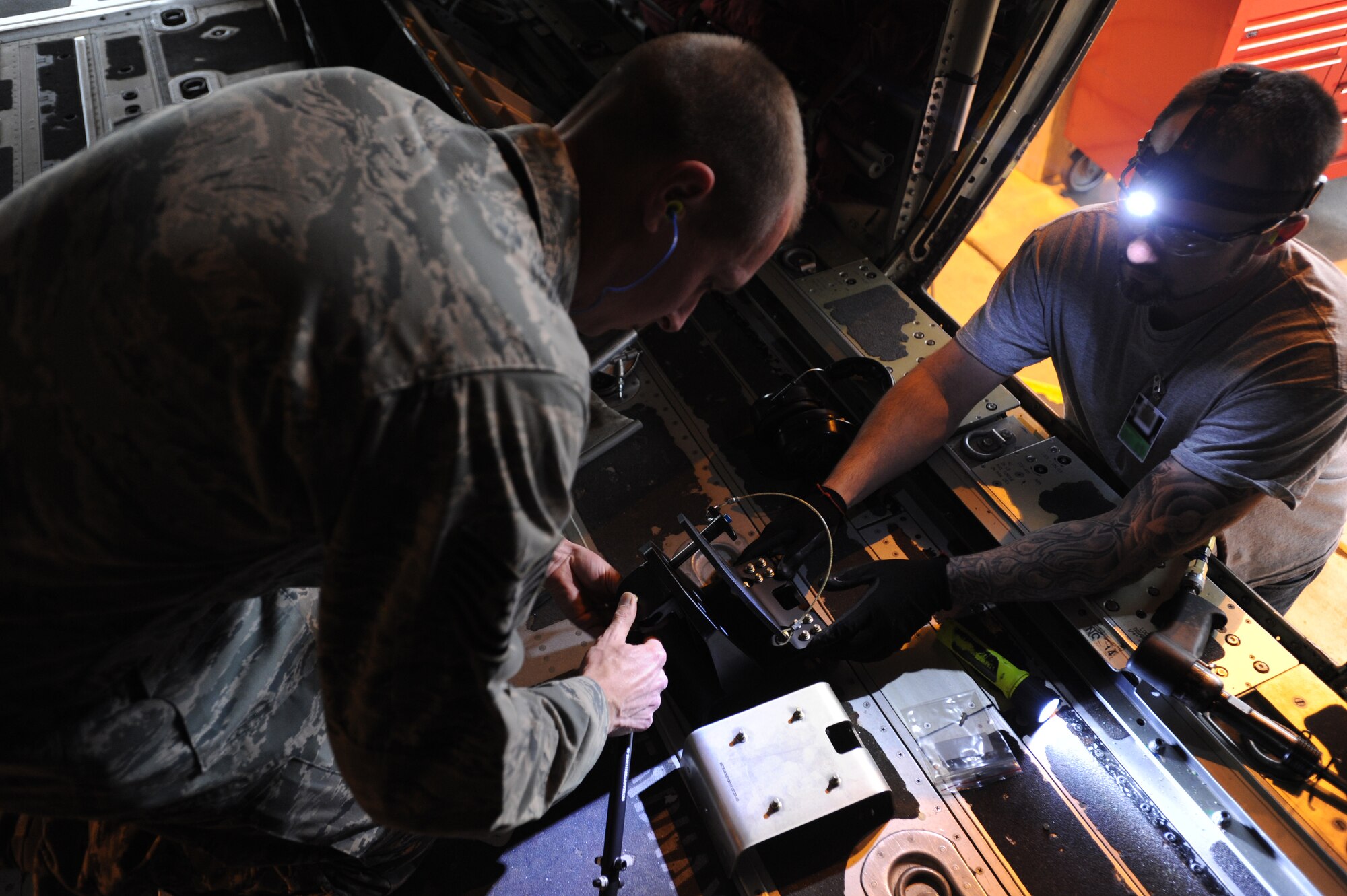 Tech. Sgt. Ryen Yokom (left), 86th Aircraft Maintenance Squadron crew chief, and Zach Edens, 560th Aircraft Maintenance Squadron mechanic from Robbins Air Force Base, Georgia, install a new seat into a C-130J Super Hercules as part of the Time Compliance Technical Order configuration April 4, 2014, at Ramstein Air Base, Germany. The new seat will enable loadmasters to have an approved seat for takeoffs and landings and will increase their survivability in the event of a hard landing or crash. The new seat will also allow the loadmaster to safely scan for surface-to-air weapons while in flight.(U.S. Air Force photo/Airman 1st Class Holly Mansfield)