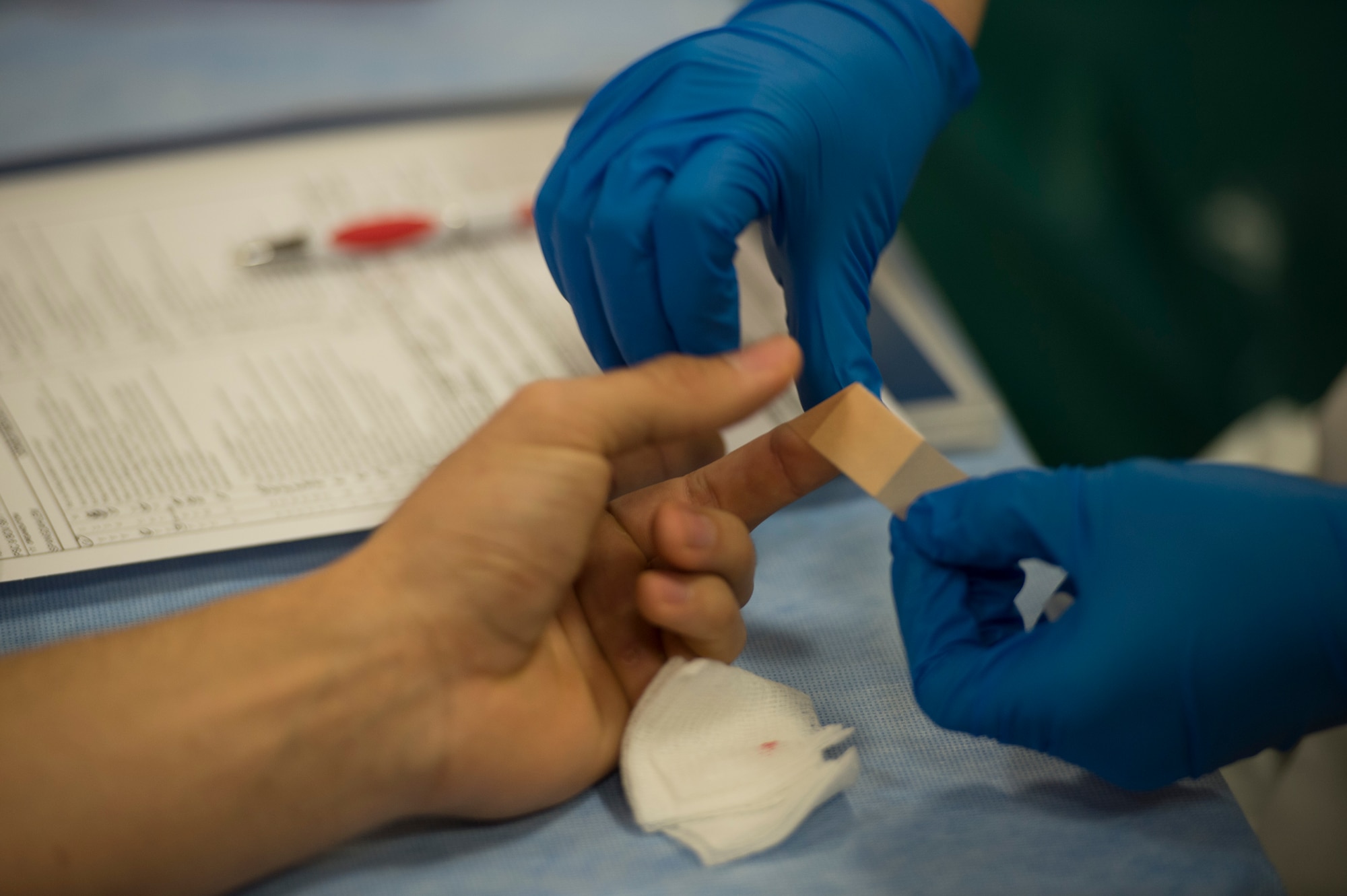 A Landstuhl Regional Medical Center laboratory technician applies a bandage to a donor’s finger in the Brick House Community Center during the Armed Services Blood Program blood drive at Spangdahlem Air Base, Germany, Nov. 18, 2014. A small sample of blood is extracted from the donor’s finger checking iron levels in the body before they are approved to give blood. (U.S. Air Force photo by Staff Sgt. Christopher Ruano/Released) 
