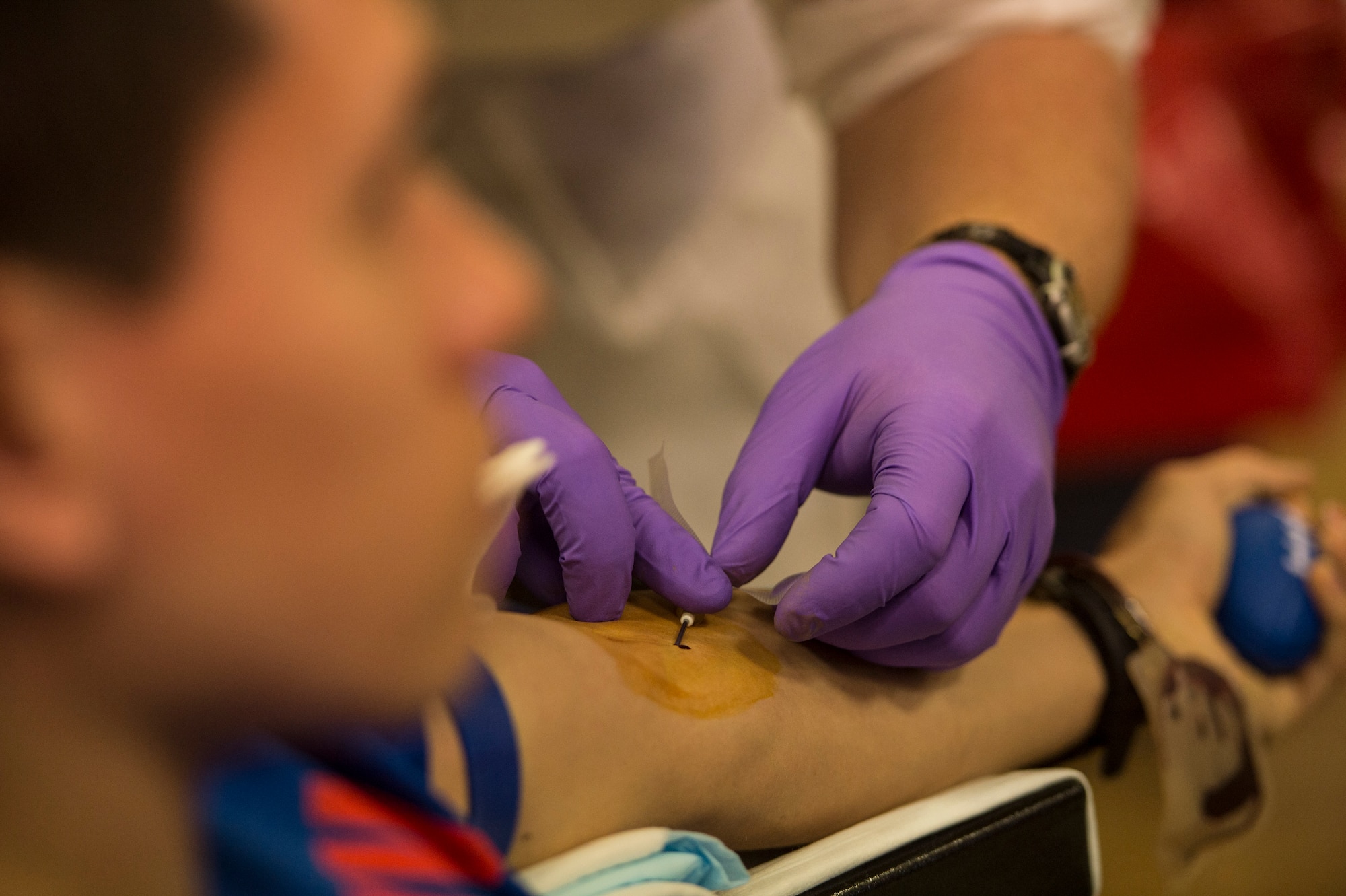 A Landstuhl Regional Medical Center laboratory technician inserts an intravenous line into a donor’s arm in the Brick House Community Center during the Armed Services Blood Program blood drive at Spangdahlem Air Base, Germany, Nov. 18, 2014. The blood drive is held here quarterly by the LRMC staff to support the Armed Services Blood Program. The donated blood is sent to forward operating bases and military medical agencies around the world to continually support the U.S. military. (U.S. Air Force photo by Staff Sgt. Christopher Ruano/Released)
