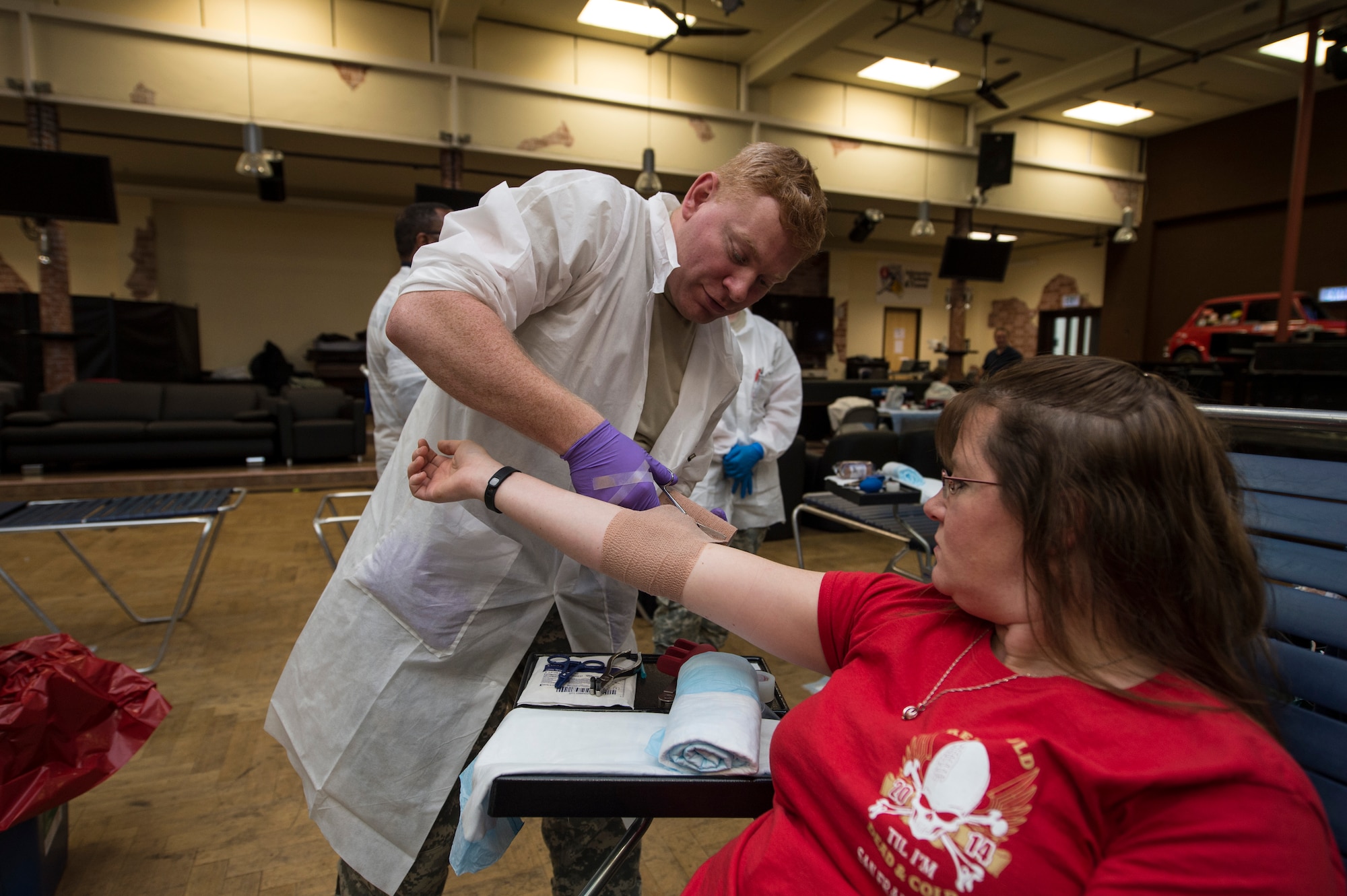 A Landstuhl Regional Medical Center laboratory technician bandages up a blood donor’s arm in the Brick House Community Center during the Armed Services Blood Program blood drive at Spangdahlem Air Base, Germany, Nov. 18, 2014. Donors were provided with drinks and food during their 15 minute recuperation time after donating one pint of their blood. (U.S. Air Force photo by Staff Sgt. Christopher Ruano/Released)